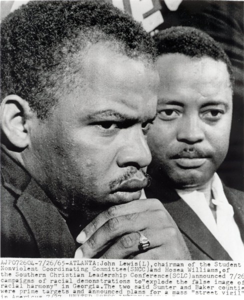 Photographic print of John Lewis and Hosea Williams in close-up, both wearing suits, with a typed press caption visible along the bottom edge