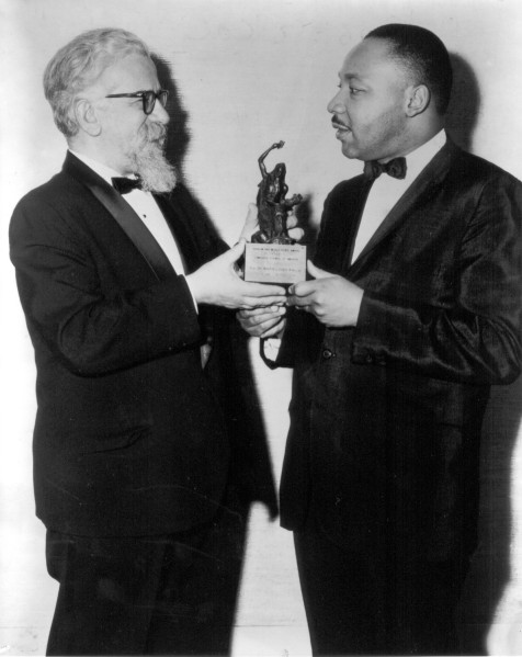 Photographic print of Rabbi Abraham Heschel and Dr. Martin Luther King Jr. in tuxedos, both holding a small figurine trophy with an engraved plaque