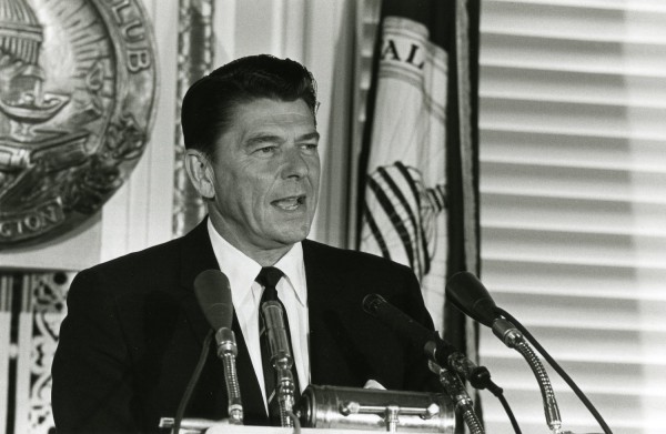 Photographic print of Ronald Reagan speaking at a podium with multiple microphones, the National Press Club seal visible in the background