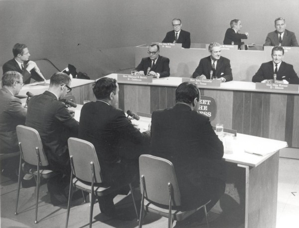Photographic print of six governors seated at tiered panelist tables with nameplates facing journalists at a "Meet the Press" television studio set
