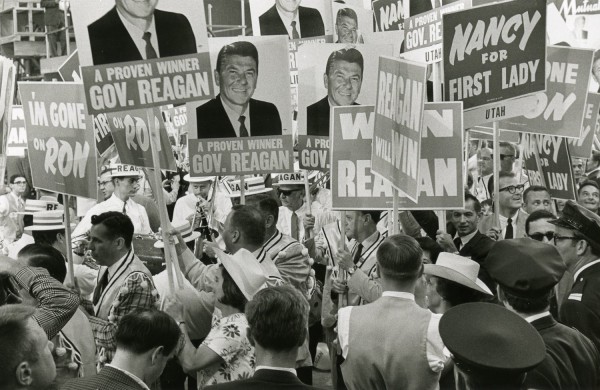 Photographic print of a crowd holding campaign signs reading 'A Proven Winner Gov. Reagan' and 'Nancy for First Lady' at a political convention