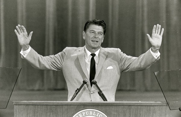 Photographic print of Governor Ronald Reagan at a podium with two microphones, arms raised wide, speaking at the Republican National Committee