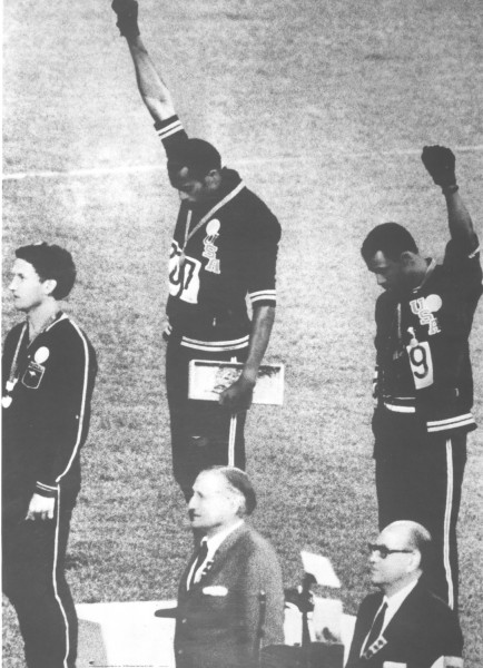 Photographic print of Tommie Smith and John Carlos on the Olympic medal podium, each raising a black-gloved fist, wearing USA uniforms and medals