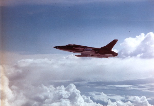 Photographic print of an F-105 Thunderchief jet aircraft in flight above a dense cloud layer under a blue sky