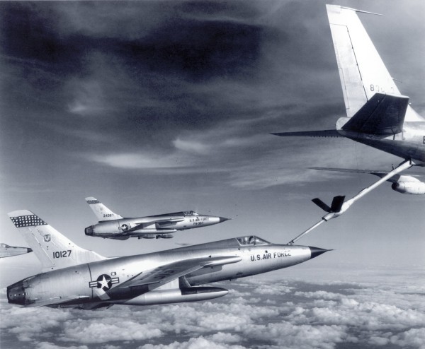 Photographic print showing three U.S. Air Force F-105 Thunderchief jets flying in formation above clouds, one connected to a refueling boom extending from a KC-135 tanker overhead