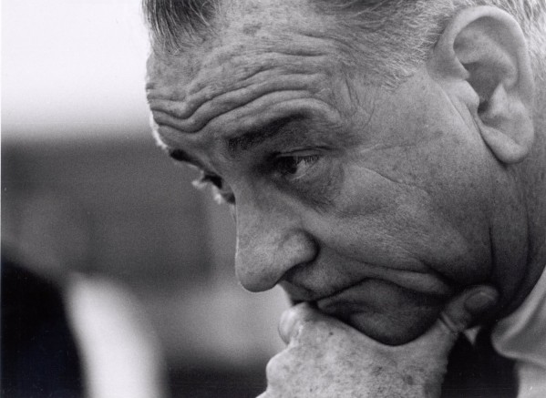 Black-and-white close-up photograph of an older man in profile, gazing downward with his hand resting under his chin